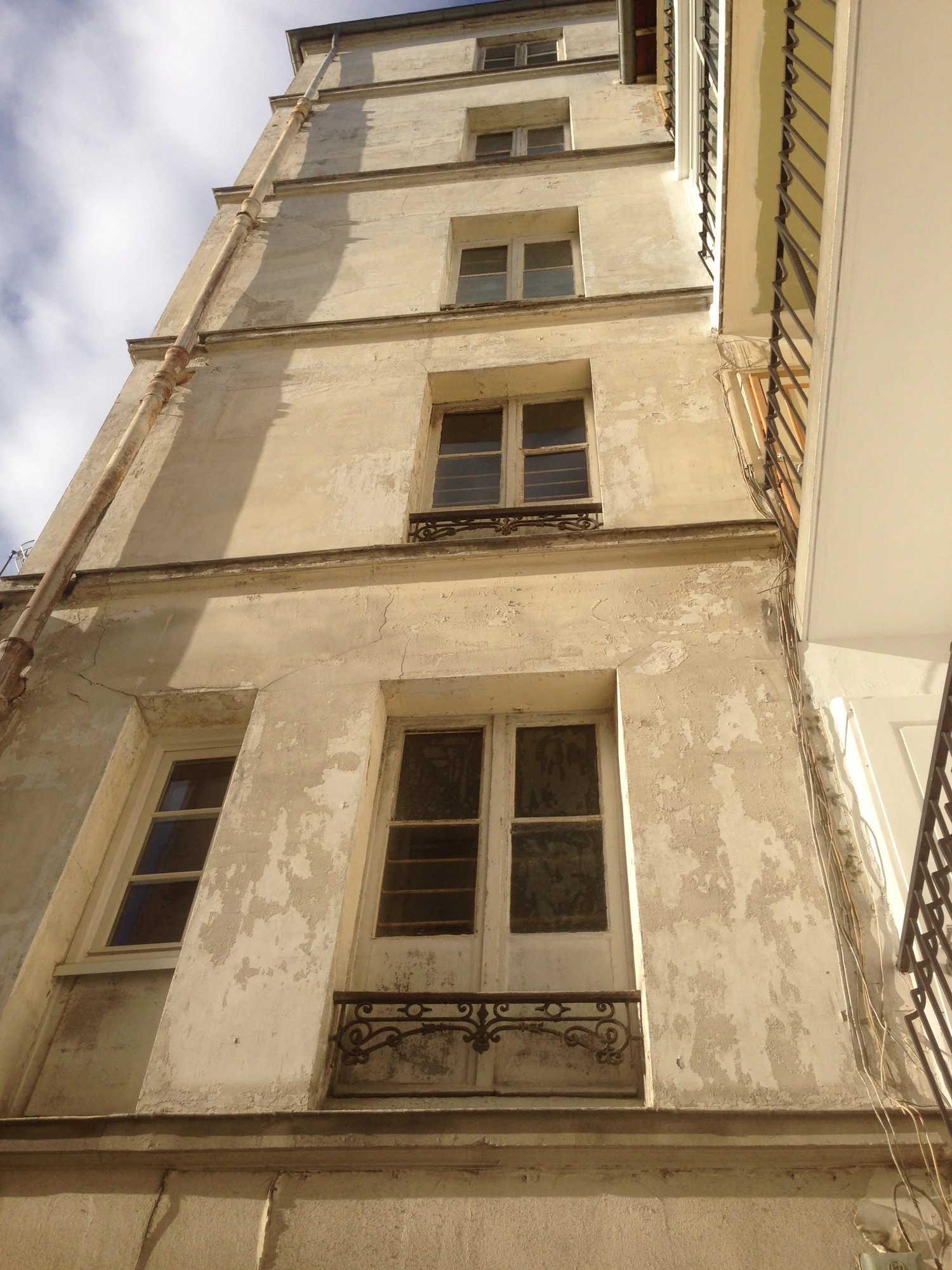 Façade sur cour d'une copropriété à Paris 13e avant ravalement : support très dégradé, fissures et enduit qui s'écaille Façade sur cour d'une copropriété à Paris 13e avant ravalement : support très dégradé, fissures et enduit qui s'écaille